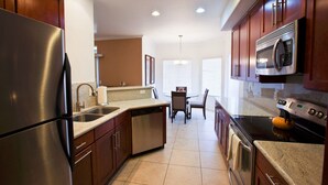 A modern kitchen with stainless steel appliances, wooden cabinets, and a dining area with a table and chairs. - Paradise Found By Signature Vacation Rentals (Scottsdale)
