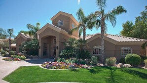 A large, two-story house with a tiled roof, surrounded by well-maintained lawns and a variety of colorful flowers. - Paradise Found By Signature Vacation Rentals (Scottsdale)