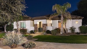 A two-story house with a stone facade, a front entrance with a door, and a well-maintained lawn. - Palm Valley By Signature Vacation Rentals (Goodyear)