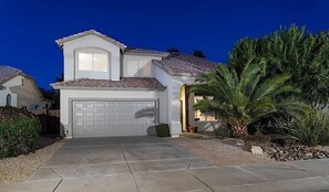 A two-story house with a garage, a driveway, and a well-maintained garden with a palm tree. - Painted Horizon By Signature Vacation Rentals (Scottsdale)