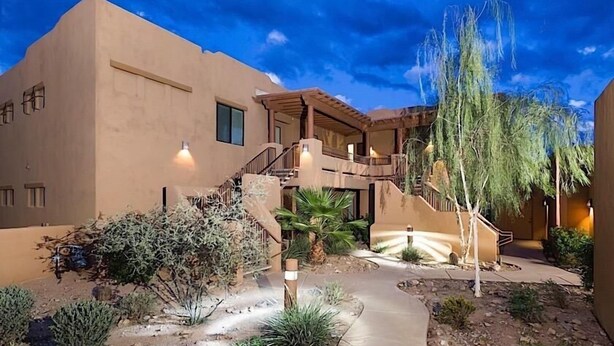 A building with a stucco exterior, a covered outdoor area with stairs, and a variety of desert plants. - Overlook Chalet By Signature Vacation Rentals (Scottsdale)