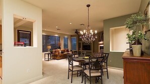 A spacious living room with a dining area, a chandelier, and a large window with blinds. - Overlook Chalet By Signature Vacation Rentals (Scottsdale)