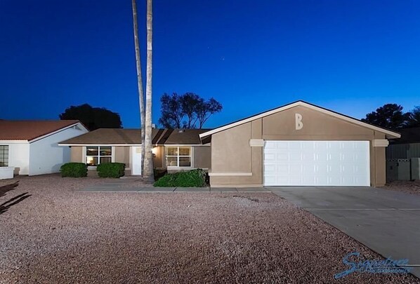 A two-story house with a garage, a well-maintained lawn, and a clear night sky.