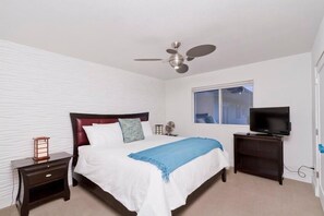A bedroom with a bed, a ceiling fan, a TV, a window, and a nightstand. - Old School By Signature Vacation Rentals (Scottsdale)