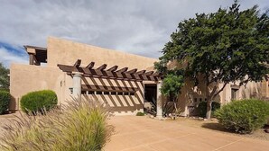 A modern building with a unique pergola entrance, surrounded by landscaped gardens and a clear sky. - Northstar By Signature Vacation Rentals (Scottsdale)