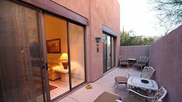 An outdoor patio with sliding glass doors, a sofa, and a table with chairs. - Northstar By Signature Vacation Rentals (Scottsdale)