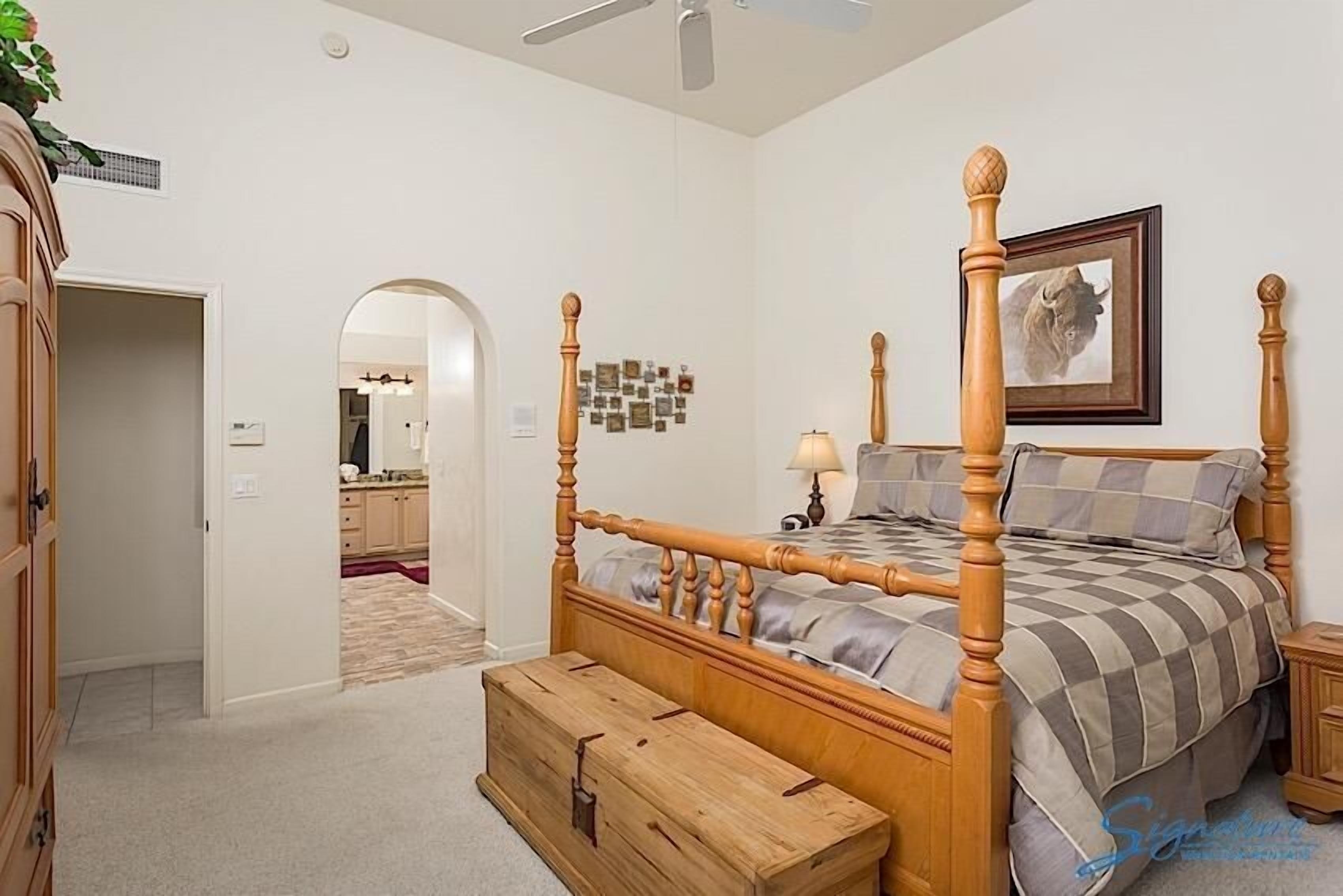Une chambre à coucher avec un lit à baldaquin, une commode en bois et un tableau encadré accroché au mur.