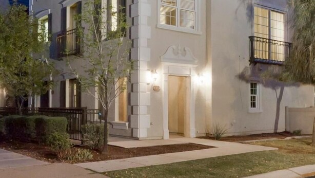A two-story residential building with a symmetrical facade, a central entrance with a decorative arch, and a small balcony on the upper floor.