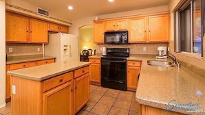 Una cocina con armarios de madera, una estufa negra, un microondas y un lavamanos.