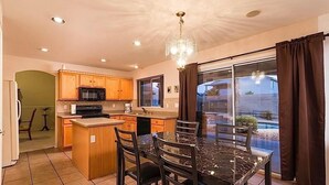 Una cocina con armarios de madera, un microondas, una estufa y una mesa de comedor de vidrio con sillas.