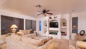 Una sala de estar con sofá, mesa de centro, televisor y objetos decorativos.