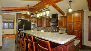 A spacious kitchen with a large island, wooden cabinets, and a stone countertop. - Majestic Carefree Home By Signature Vacation Rentals (Carefree)