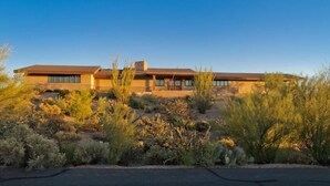 A modern two-story house with a flat roof and large windows, surrounded by desert vegetation. - Majestic Carefree Home By Signature Vacation Rentals (Carefree)