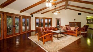 A spacious living room with wooden beams, leather sofas, and a large window with glass doors. - Majestic Carefree Home By Signature Vacation Rentals (Carefree)