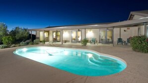 A modern house with a swimming pool, outdoor seating, and a well-lit patio area. - Majestic Carefree Home By Signature Vacation Rentals (Carefree)