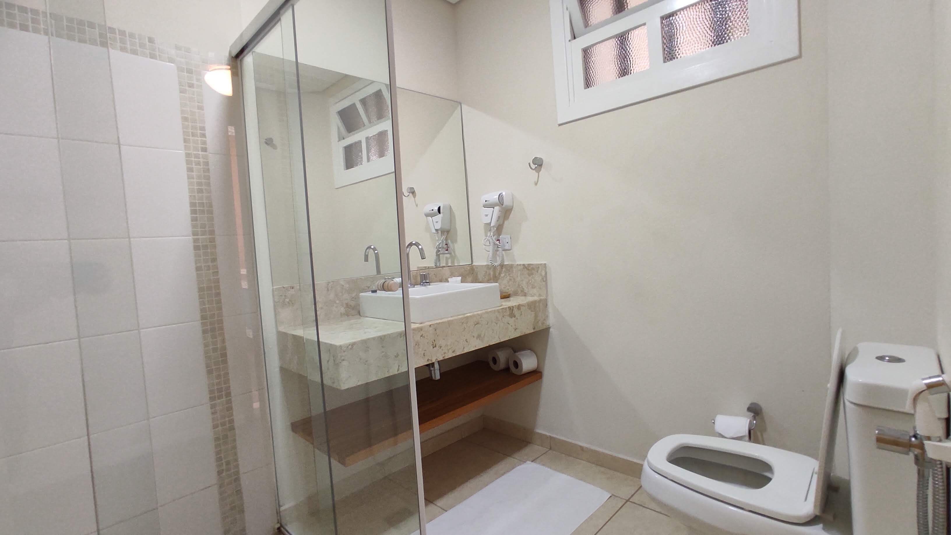A bathroom with a glass-enclosed shower, a sink with a mirror, and a toilet.