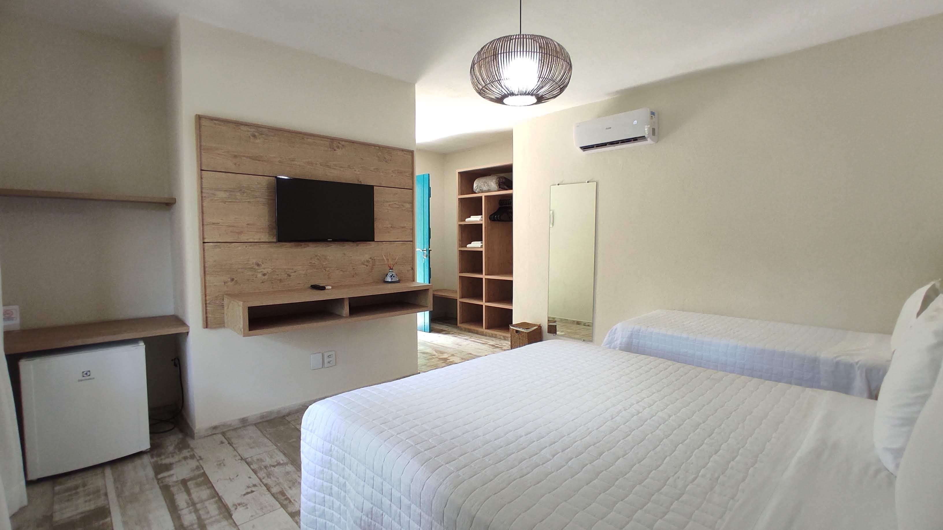 Une chambre à coucher comprenant un lit, un téléviseur fixé sur un panneau en bois, une armoire et un miroir.