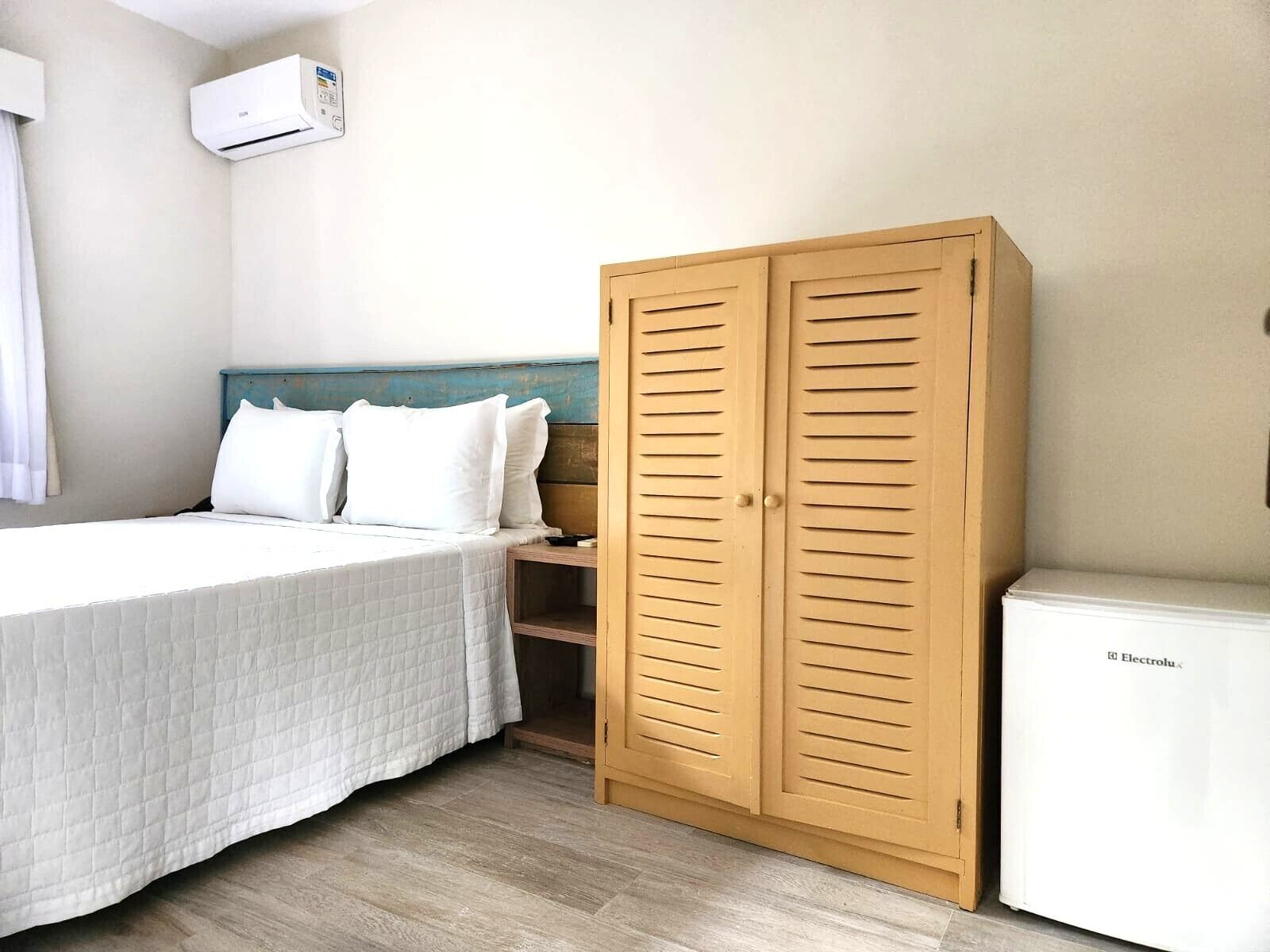 A bedroom with a bed, a wardrobe, and a white appliance.