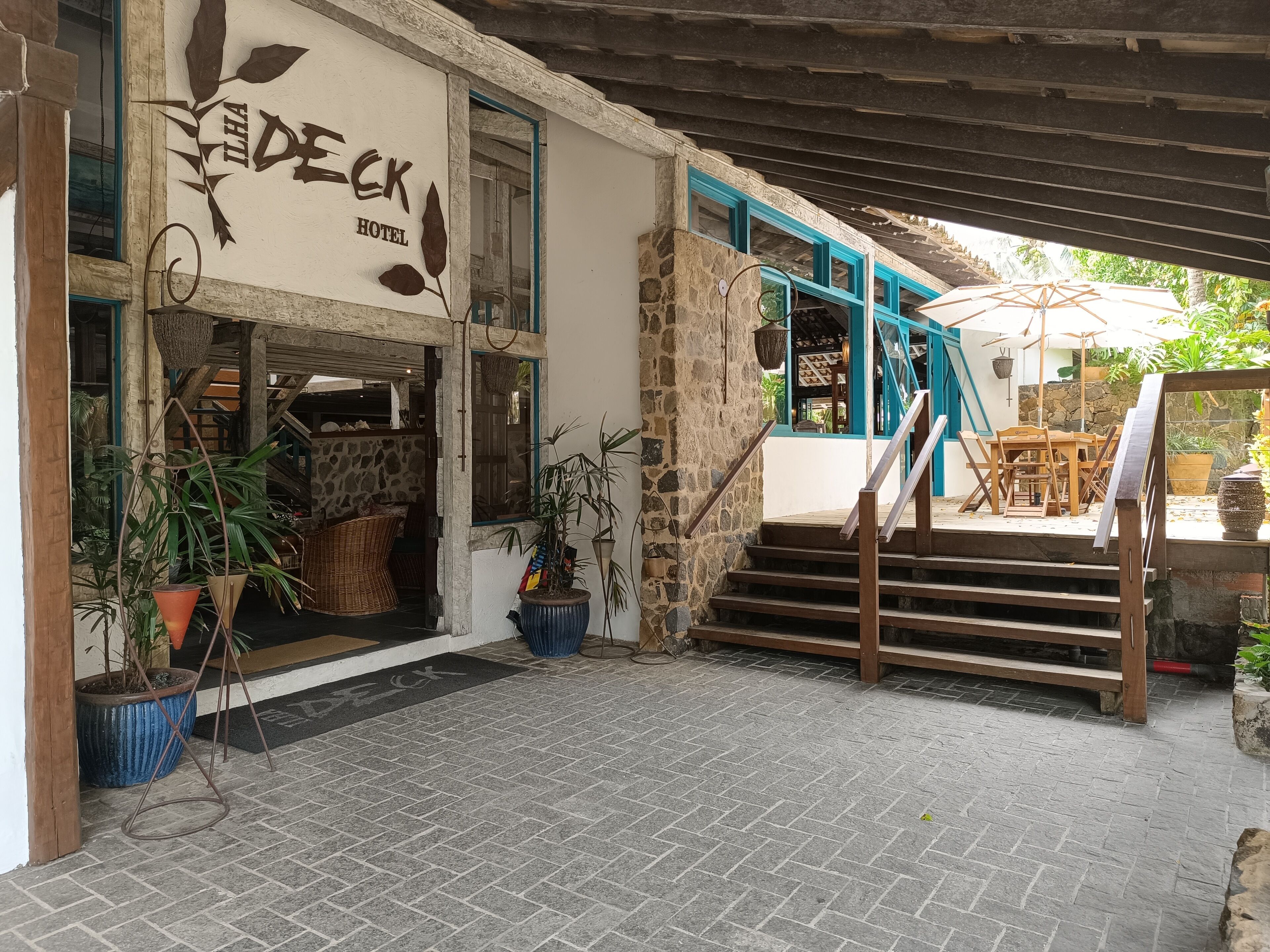 A hotel entrance with a stone facade, a wooden staircase, and outdoor seating.