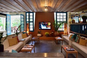 Un salón acogedor y bien iluminado con asientos cómodos, un televisor y varias plantas.