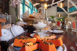 Een buffettafel met diverse gerechten, waaronder een middelpunt van plakjes papaja bestrooid met zwarte zaden.
