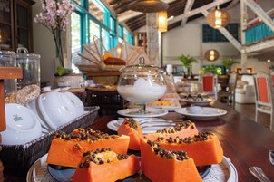 Uma mesa de buffet com diversos pratos, incluindo uma peça central de mamão em fatias coberto com sementes pretas.
