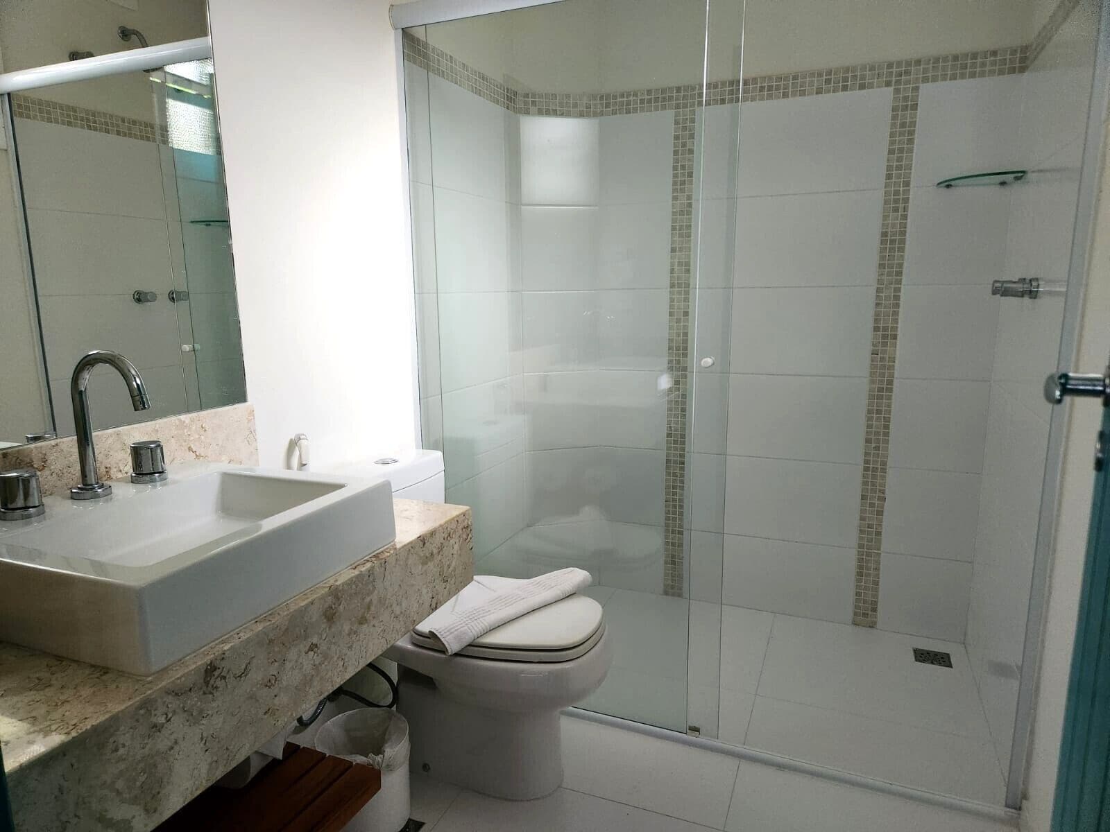 Un baño moderno con ducha acristalada, lavabo blanco y retrete.