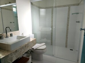 A modern bathroom with a glass-enclosed shower, a white sink, and a toilet.