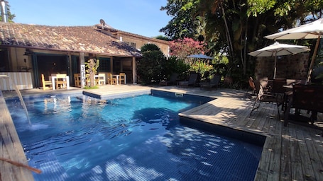 Una piscina al aire libre, sillones reclinables de piscina