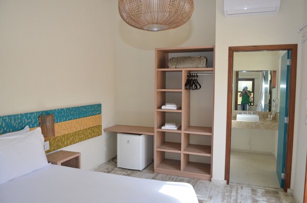 Une chambre à coucher avec un lit, un petit bureau, une armoire et un miroir.