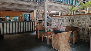 A lobby with wicker furniture, a stone wall, and a staircase.
