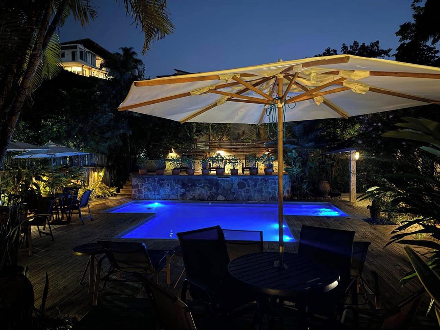 An outdoor pool area with a stone wall, lounge chairs, and umbrellas.