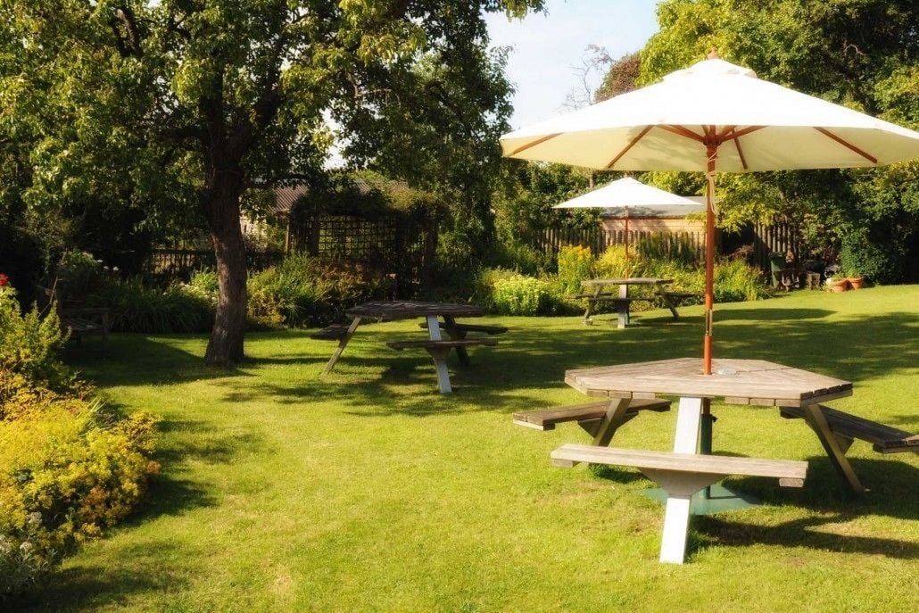 A garden with picnic tables and umbrellas.