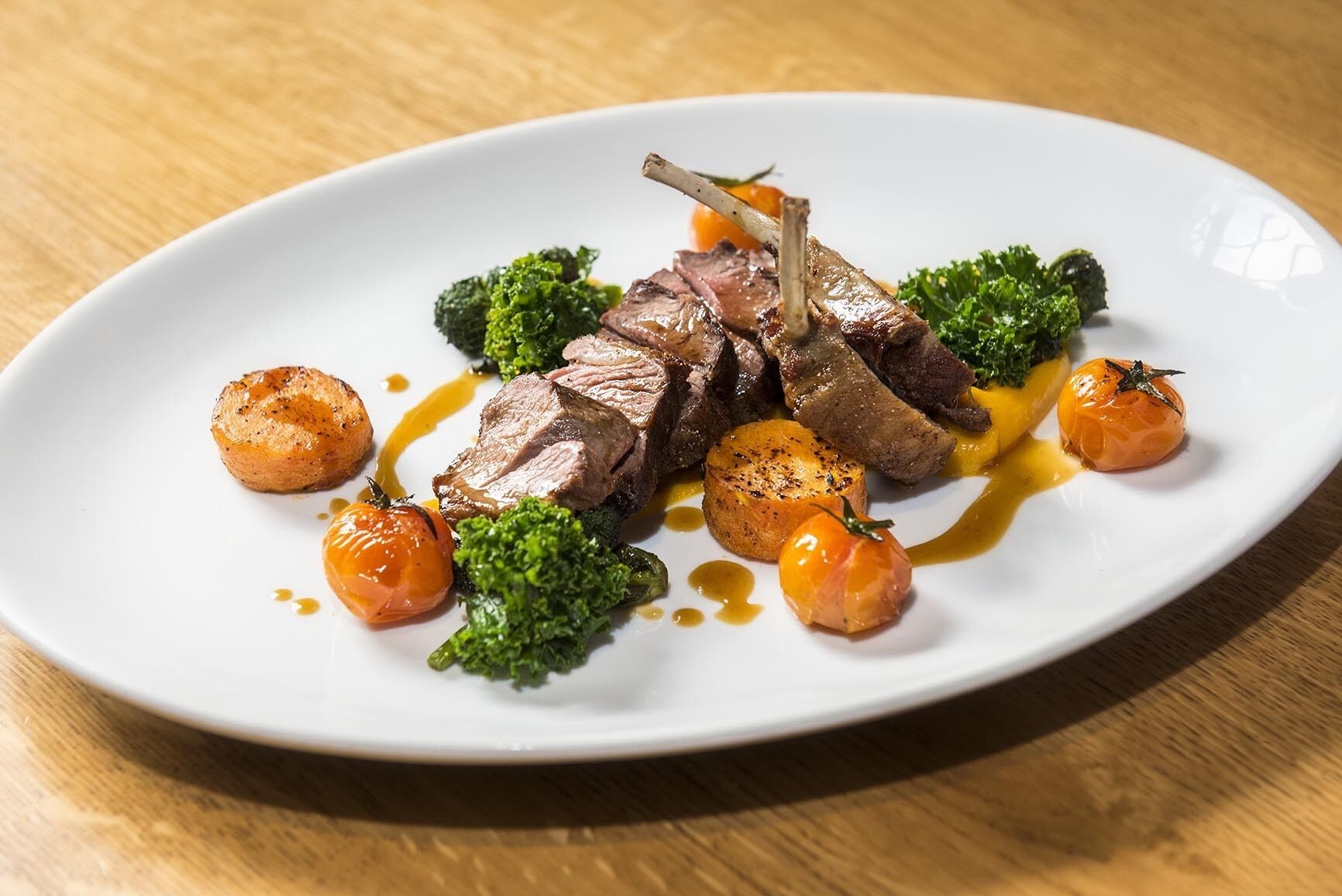A plate of food with meat, broccoli, and small round vegetables, served on a white plate.