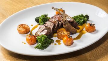A plate of food with meat, broccoli, and small round vegetables, served on a white plate.