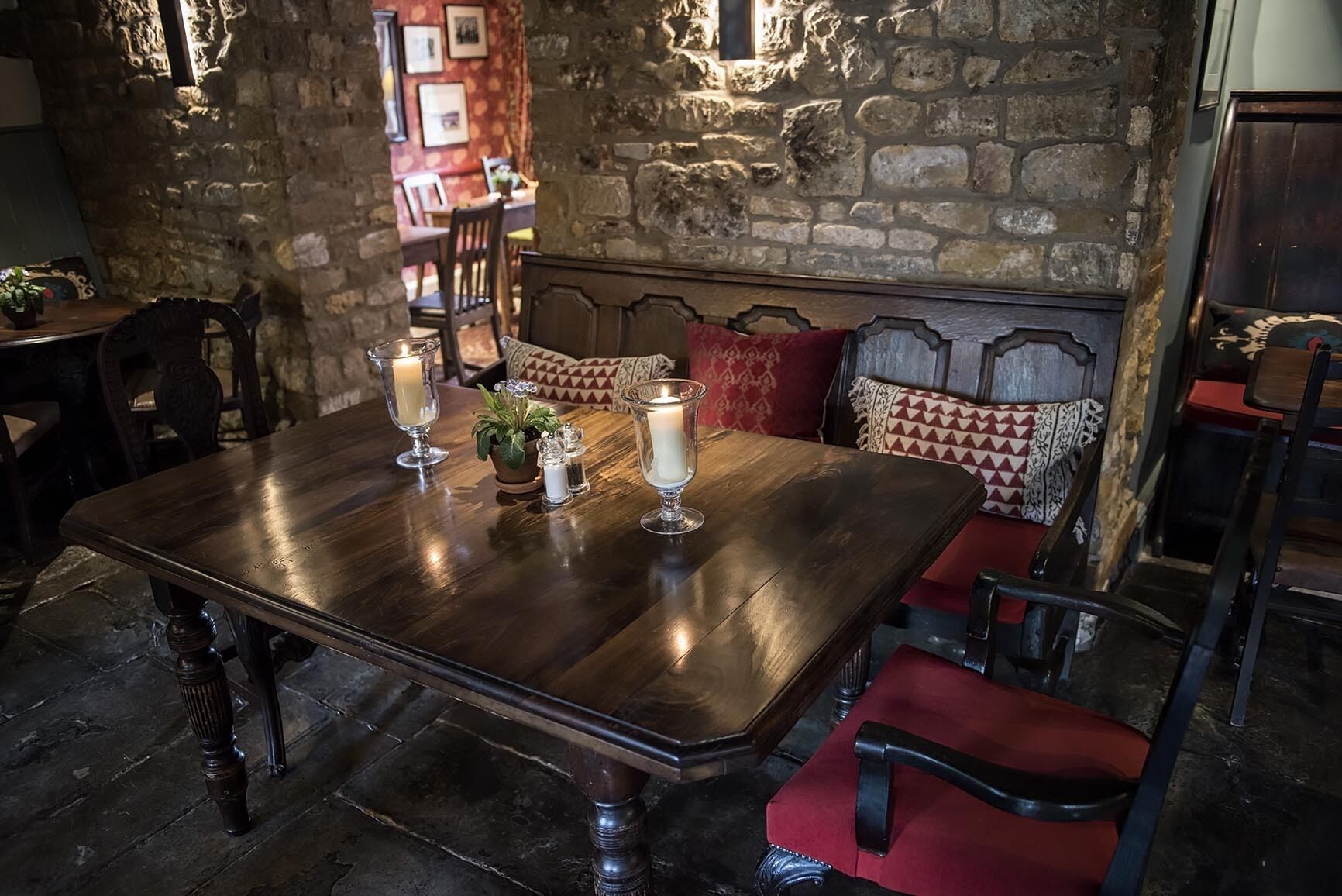 Un coin repas rustique avec une table en bois, des bougies et des chaises d’époque.
