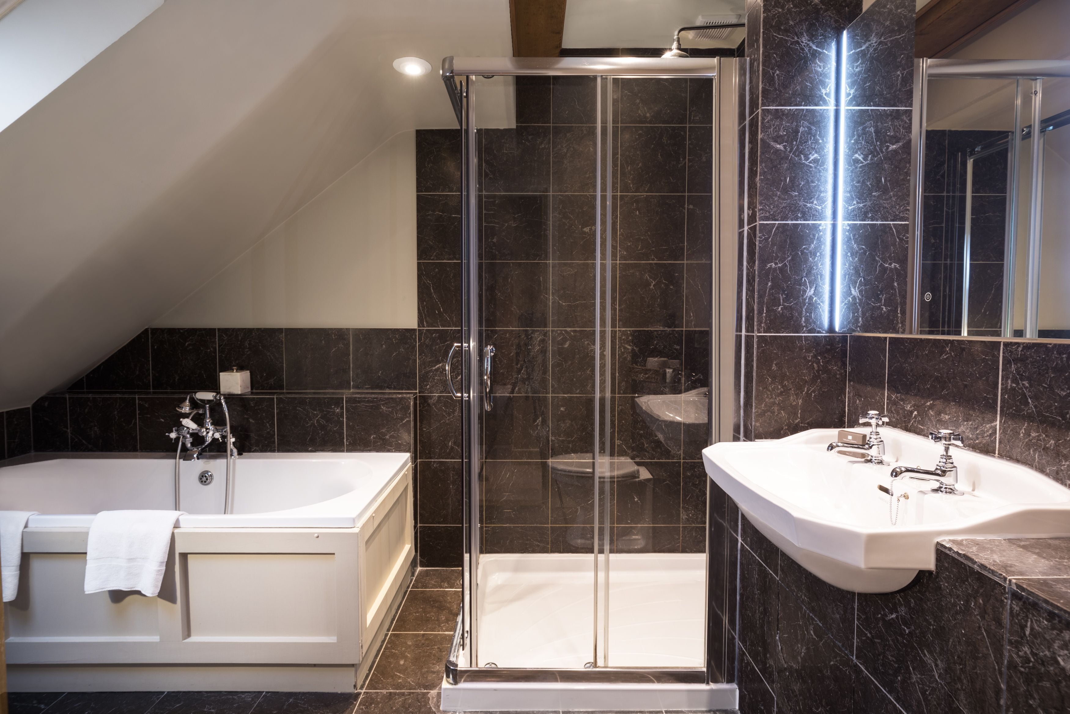 A modern bathroom with a glass-enclosed shower, a freestanding bathtub, and a vanity with a sink.