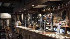 A bar area with wooden bar stools, a variety of bottles and glasses on shelves, and a Pepsi dispenser. - The Howard Arms (Shipston on Stour)