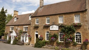 A stone building with a sign reading "Country Dining at The Howard Arms" and flower boxes on the windowsills. - The Howard Arms (Shipston on Stour)