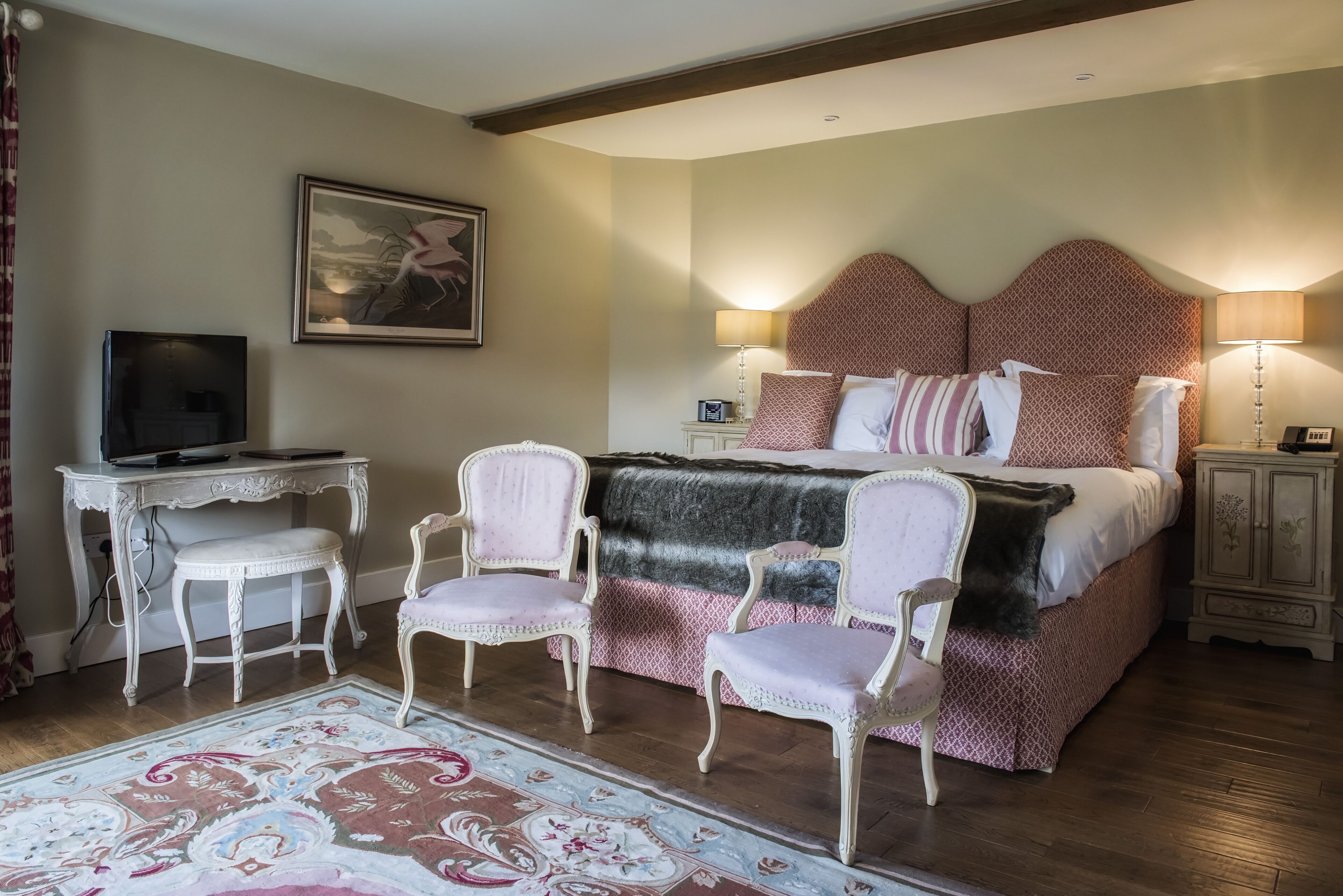Une chambre à coucher avec un grand lit, deux tables de chevet, un bureau avec une chaise et un téléviseur.