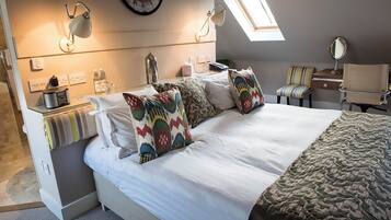 A modern bedroom with a large bed, a clock on the wall, a skylight, and a desk with a lamp.