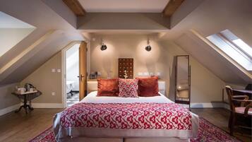 A bedroom with a large bed, two pendant lights, a skylight, and a view of a hallway.