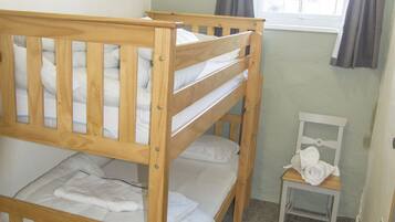 A bunk bed room with a small chair and a window with curtains.