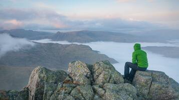 A person sitting on rocks overlooking a mountainous landscape with fog.