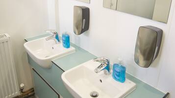 A bathroom with two sinks, a mirror, and a hand sanitizer dispenser.