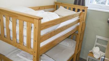 Un letto a castello in una stanza con una finestra e una piccola sedia.