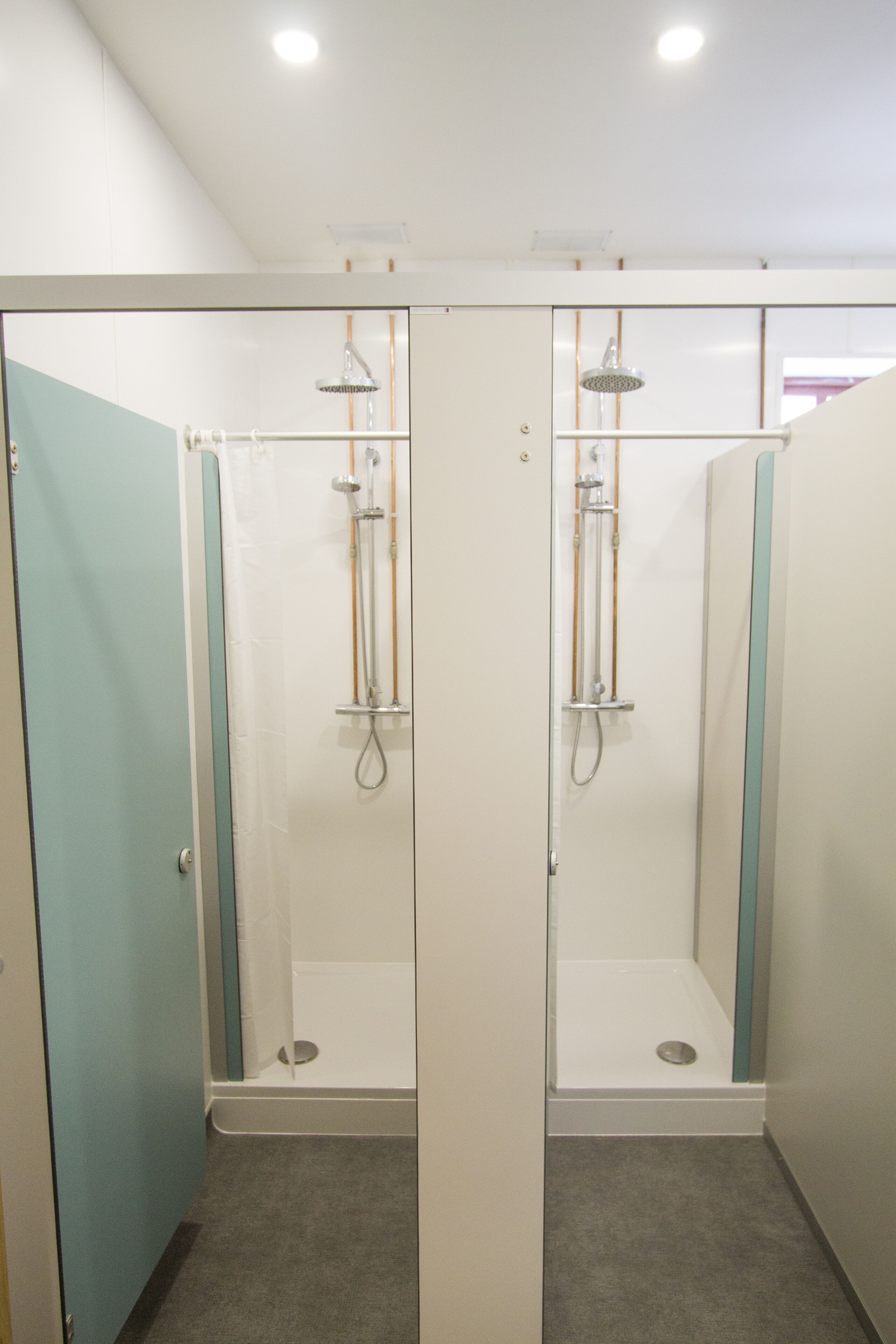 Un baño con dos cabinas de ducha, cada una con mampara de vidrio y ducha de mano.