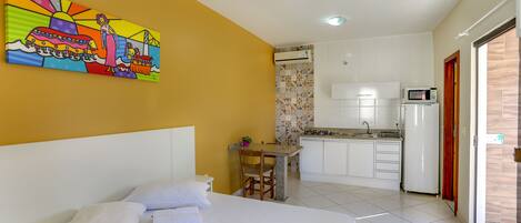Una habitación de hotel con una cama, una pequeña mesa con sillas, una kitchenette y un mural colorido en la pared.