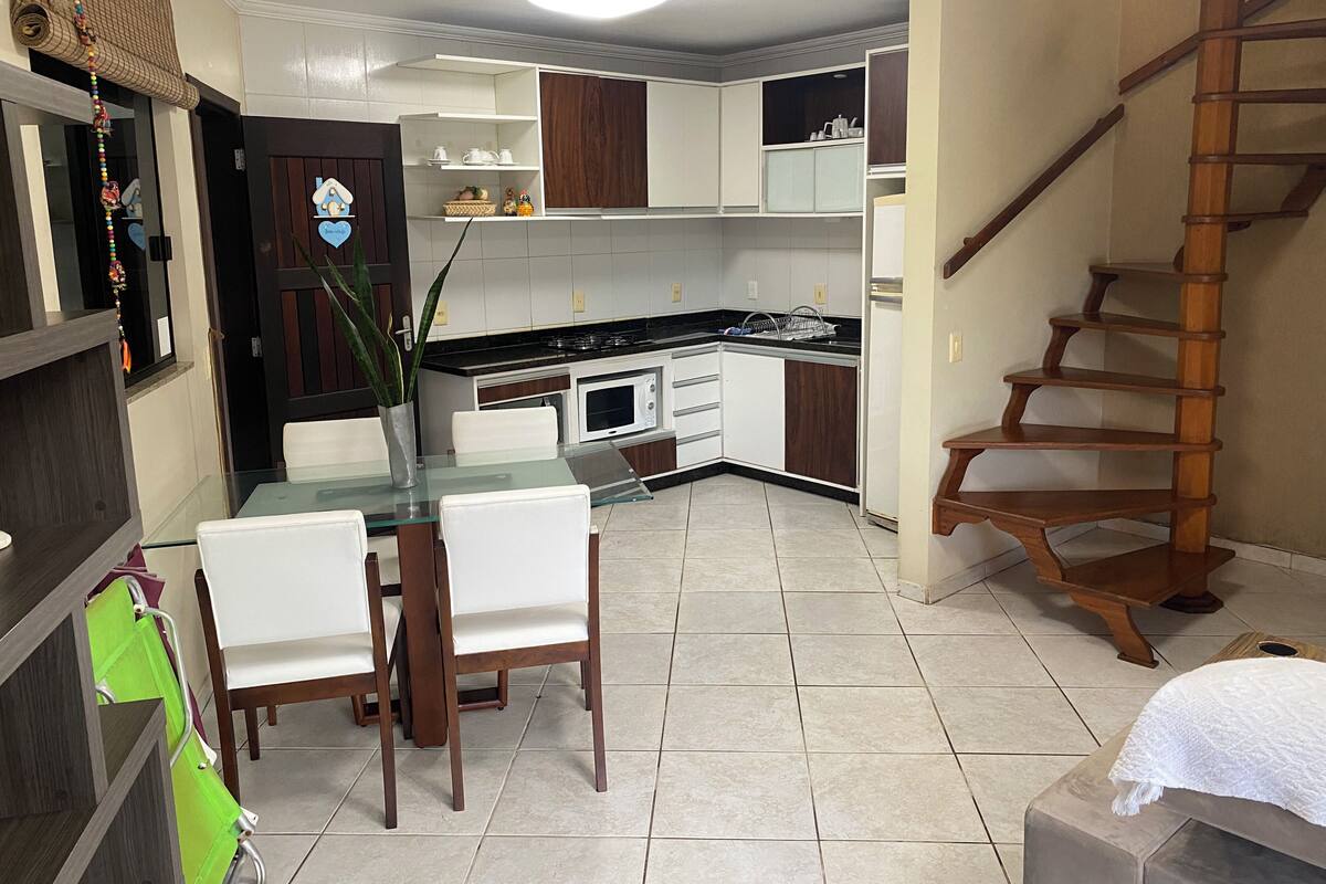 A modern kitchen with white cabinets, a black countertop, and a wooden staircase.