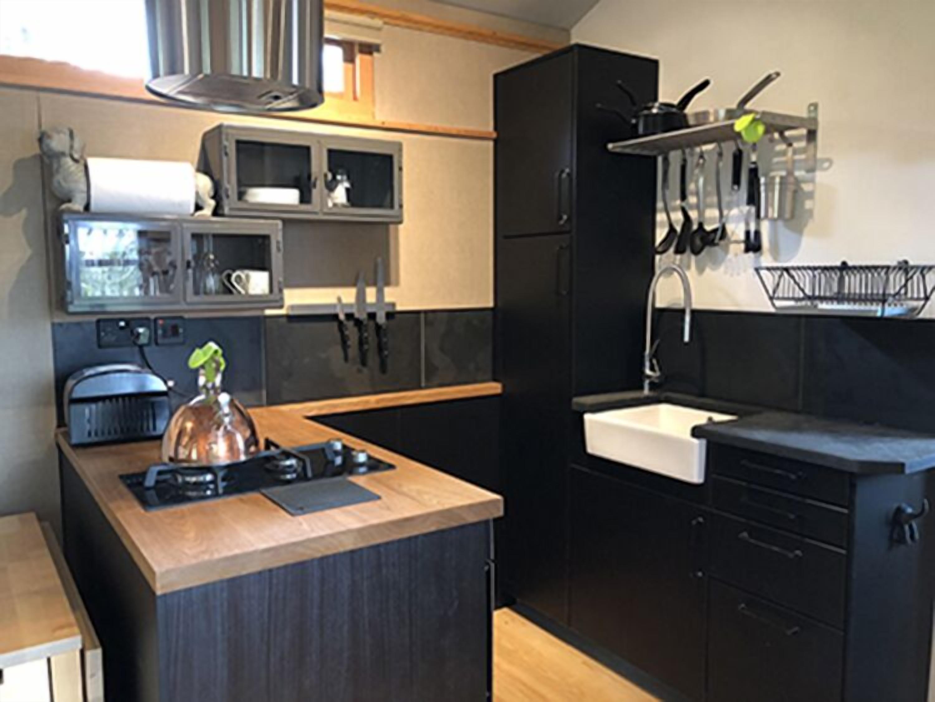 A modern kitchen with a central island, black cabinetry, and a stainless steel sink.